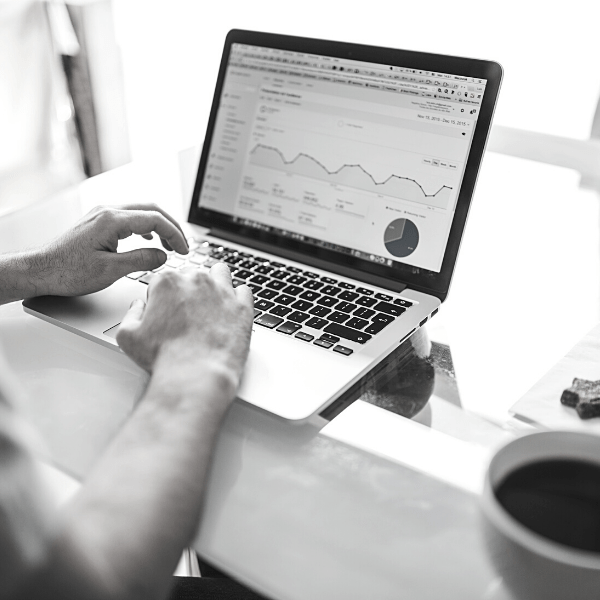 Close up of hands on the keyboard of a laptop. Graphs are displayed on the screen.